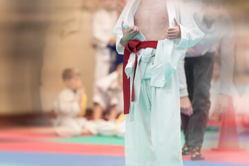 Naklejka premium Sports background concept for martial arts with shallow depth of field and motion blur effect. An athlete in a white kimano with a red belt on the tatami before the fight.