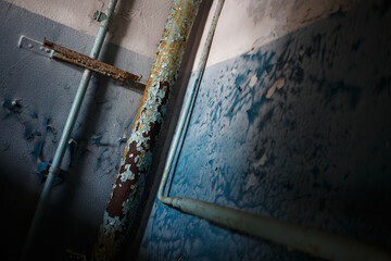 The interior of an abandoned house. Peeling paint on walls and pipes. Gloomy mood. A dark room with blue walls. Oblique angle.