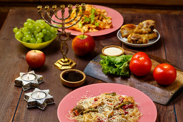 Shabbat set table with traditional food, fruits, candles and menorah.