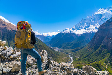 Female Trekker with large backpack looking at view on the Annapurna Circuit Trek on a sunny cloudless fall day