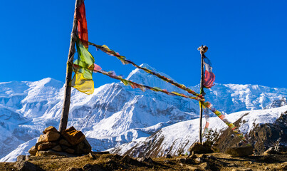 Prayer flags blowing in the wind with snowy Annapurna mountain range in the distance