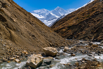 Fototapeta na wymiar River flowing with snowy mountain peaks on the Annapurna Circuit Trek, Nepal