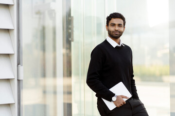 Portrait of young confident Indian businessman holding digital tablet looking at camera, copy space  