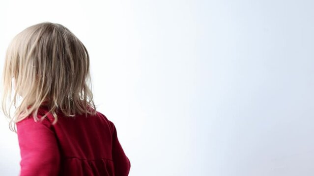 Portrait of cheerful caucasian child girl 3-4 years old showing tongue making faces at camera, fooling around, squint her eyes . Preschool little girl