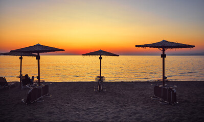 Greece Chalkidiki. Picturesque sunset at coast Aegean sea. Beach umbrells on the Sea resort for vacation