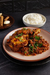 Chicken curry with chicken legs, onions and tomatoes, served on a plate.