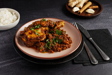 Chicken curry with chicken legs, onions and tomatoes, served on a plate.