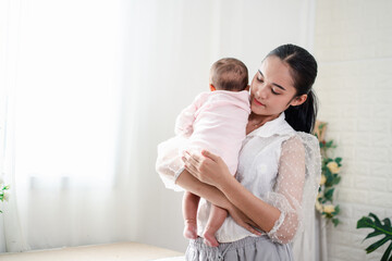 Mother Parenting and newborn birth life. Mom and baby boy playing in sunny bedroom, Family having fun together. childcare, maternity concept.