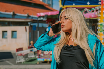 girl with mobile phone in amusement park or fair
