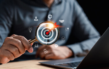 Businessman using magnifying glass focus to target icon which for planning development leadership and customer target group concept