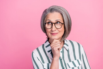 Photo portrait of dreamy cute retired businesswoman white hair touch chin look empty space genius idea isolated on pastel pink color background