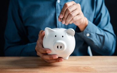 Man putting coin to white piggy bank for deposit banking of investment , retirement planning future...