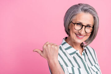 Photo of pensioner cheerful woman executive director indicate thumb empty space useful tips present new law company isolated on pink color background