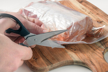 Cut the vacuum packaging with the product with scissors. Remove the piece of meat from the plastic...