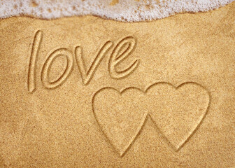 Words written in beach sand. The word LOVE written in the sand on the beach with the ocean as the background. Love is all you need. Everyone Loves the beach. Love.