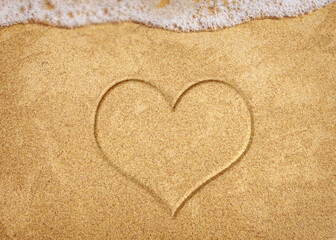 Fototapeta na wymiar Heart Symbol On a Sand Of Beach With Soft Blue Wave On Background