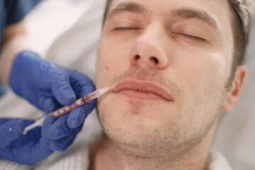 Young man in cosmetologist cabinet has a face injection for lifting