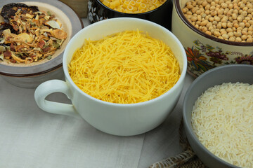 Yellow noodles in bowl on a straw background. Vegetarian organic product. Vintage view.