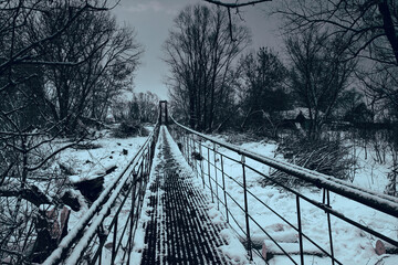 photo of a pedestrian suspension bridge over the frozen surface of the river