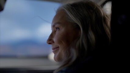 Portrait of beautiful 60s mature senior grey haired Caucasian female riding in a car on a passenger...