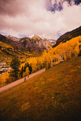 View from a gondola of people walking and scenic views in Telluride, Colorado in the fall with colorful aspen trees and purple mountain background