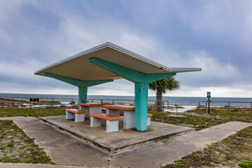 A mid-century modern style concrete picnic shelter and tables on a beach in Florida.