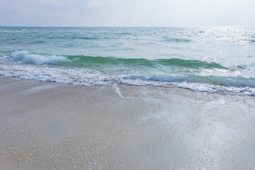 Fototapeta na wymiar Pale turquois Gulf of Mexico waves along a beach.