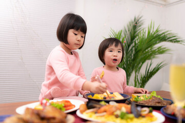 テーブルに並べられたクリスマスの料理を食べる子供