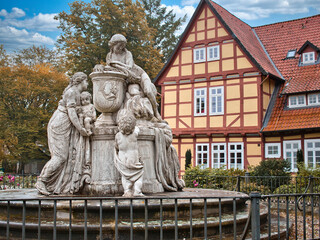 Statue of women and children by a fence with a red frame house behind