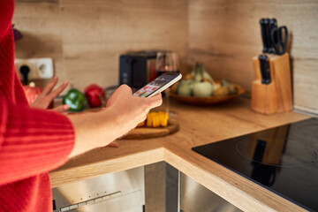 Close-up of the hands of a girl with a mobile phone in her hands in the kitchen. Search for recipes on the Internet. calorie counting app.