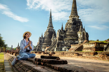 Fototapeta na wymiar Pretty happy smiling tourist young Asian woman and paying their respects in the famous ancient palace in Ayutthaya, Wat Phra Si Sanphet Thailand.