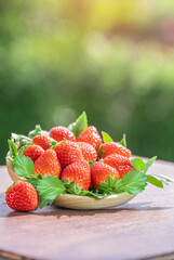 Red strawberry in wooden basket on blurred greenery background, Red Strawberries on wooden table in...