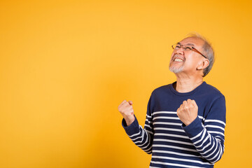 Happy Asian elder man with glasses excited say yes gesture like winner studio shot isolated on...
