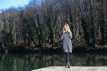 Fototapeta na wymiar Beautiful young woman is standing by the lake