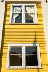 Windows. The Yellow wall with windows. Old looking yellow wall with white wooden windows with curtains.