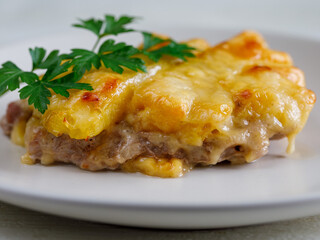 Baked Pork Steak with Pineapple grated with cheese on white plate close up