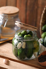 Glass jar with fresh cucumbers and other ingredients on wooden table. Canning vegetable