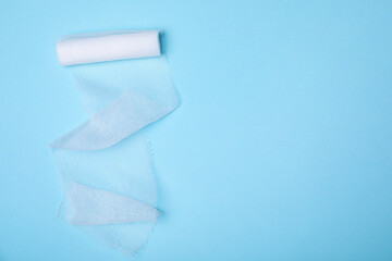 White medical bandage on light blue background, top view. Space for text