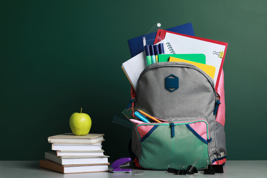 Backpack with different school stationery on white table near chalkboard - Powered by Adobe