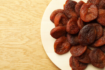 Plate of tasty apricots and space for text on wooden table, top view. Dried fruits