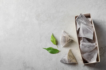 Box with tea bags and leaves on grey table, flat lay. Space for text - obrazy, fototapety, plakaty