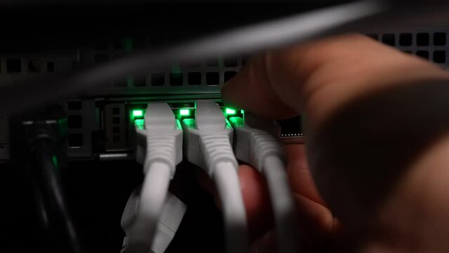 Unplugging four networking ethernet cables into network server switch by hand, Close up shot