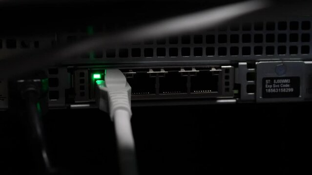 Plugging four networking ethernet cables into network server switch by hand, Close up shot