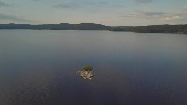 Lonely rock island in a big lake in sweden. people with a canoe on it.