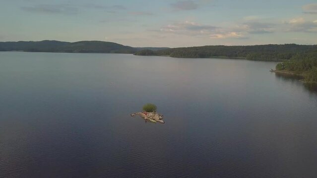 Drone circling a small cliff island in a big lake