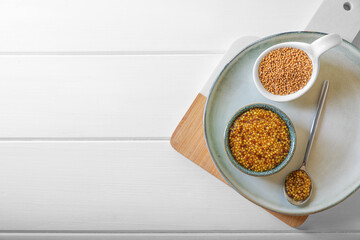 Tasty whole grain mustard on white wooden table, flat lay. Space for text