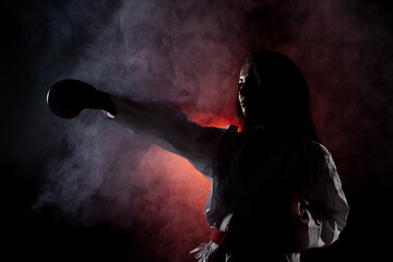 Fototapeta na wymiar beautiful girl exercising karate punch against red fog background..