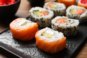 Delicious sushi rolls on black plate, closeup
