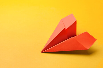 Handmade orange paper plane on yellow background, space for text