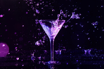 Glass of martini and splashes in neon lights on dark background, bokeh effect